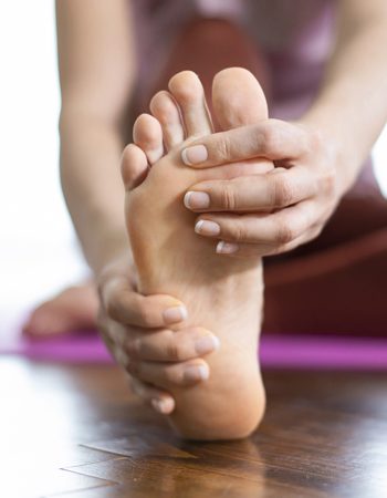Imagen de un pie haciendo una postura de yoga mientras es examinado por un podólogo deportivo