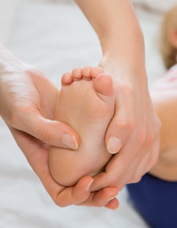Bebé con los pies en las manos de un podólogo pediátrico.